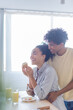 © LIGHTFIELD STUDIOS - Cheerful african american couple standing near breakfast in kitchen