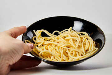 Long spaghetti in a black plate on a white background