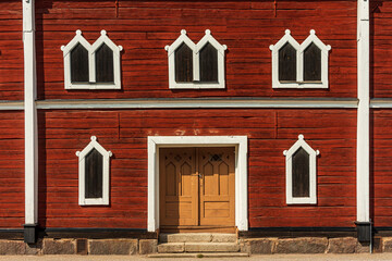 Canvas Print - Old wooden house in red timber with ornamented windows