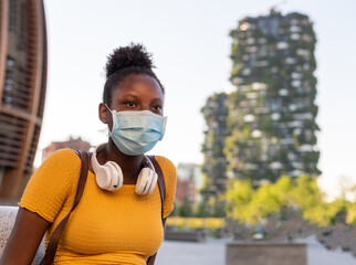 young african  woman wandering around the city, tourist with mask looking urban scene, traveler wearing facemask during Corona Virus outbreak