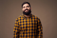 A Happy Man With A Bushy Beard Is Smiling At The Camera And A Plaid Shirt