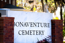 Closeup Of Bonaventure Cemetery Historic Sign In Savannah, Georgia With Brick Architecture And Palm Trees In Blurry Background In Summer