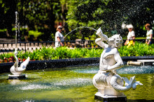 Water Fountain In Forsyth Park, Georgia With Sculpture Statues Of White Marble In Savannah, Georgia On Sunny Summer Day With People In Blurry Blurred Background