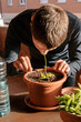 © Edgar - Hombre caucásico joven en la terraza de su casa cuidando su planta carnívora con varias plantas encima de la mesa y material para cuidarlas