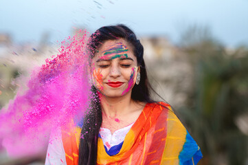 Portrait of happy Indian woman celebrating Holi with powder colours or gulal. Concept of Indian festival Holi.