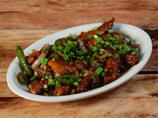 Wall Mural - Chilli Chicken is an Indian Chinese starter served over a wooden rustic background. selective focus