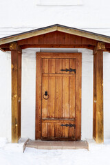 An old-fashioned porch and a wooden door set in a white brick wall.