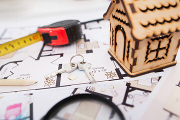 Poster - wooden toy house, keys with a tape measure and a magnifying glass on the plan of the house.