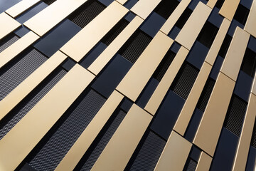 Modern, abstract facade with gold and black elements from oblique angle with sun reflection as architecture background