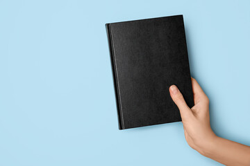 Woman holding book on color background