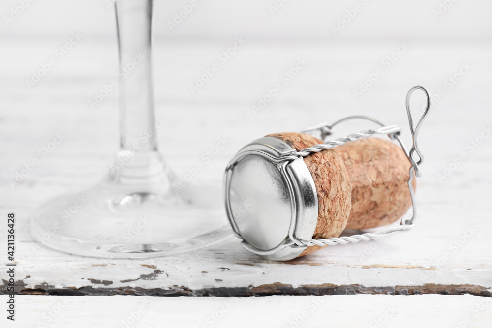 Glass and champagne cork on light wooden background, closeup