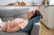 Young mom lying on on pillow on couch, resting, sleeping after completing house working. Woman napping on sofa in living room, feel fatigue, relaxing. Leisure, lazy time concept.