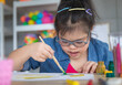 © Bangkok Click Studio - Young Asian down syndrome little girl sitting at desk with colors and painting with concentrated and calm. painting. Concept for education for disabled kid.