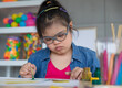 © Bangkok Click Studio - Young Asian down syndrome little girl sitting at desk with colors and painting with concentrated and calm. painting. Concept for education for disabled kid.