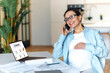 © Kateryna - Good looking pregnant mixed race adult woman is sitting near her work desk, having pleasant cellphone business conversation, gently touching her belly, looking away and smiling