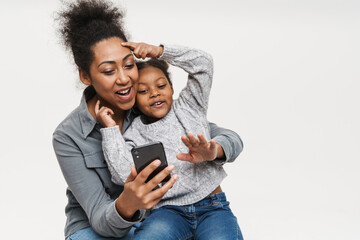 African mother and daughter making fun while using cellphone