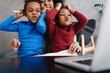 © Drobot Dean - Happy afro american mother using laptop while playing with her children