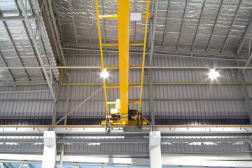 Overhead crane inside factory or warehouse. That industrial machinery or lifting equipment consist of hoist, hook and wire rope traveling on beam girder structure. For manufacturing production plant.