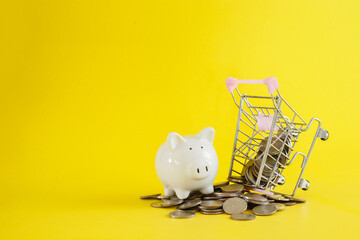 White piggy shopping cart with coins thai baht on yellow background, save or investment concept.