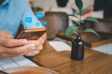 closeup man hand holding smartphone with message icon as chatting in cafe