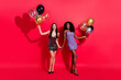 © deagreez - Full size photo of optimistic brunette ladies hold hands balloons wear dress shoes isolated on vibrant red color background