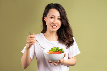 Cheerful young asian girl eating health food on background