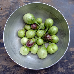 green organic brinjals in a bowl.