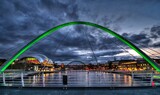 Gateshead Millenium Bridge in the foreground with the Sage and the Tyne Bridge in the background. The bridges connect Gateshead and Newcastle upon Tyne in northern England.