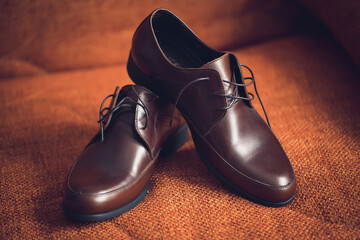 Leather stylish men's shoes with laces on a wooden floor with gold rings on a boot. Groom's wedding shoes. Classic shoes for men.