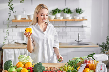 blonde female puts vegetables on scales, in kitchen at home