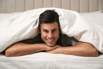 Wall Mural - Handsome man relaxing under soft blanket in bed at home