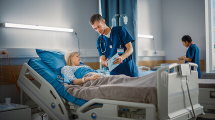 Wall Mural - Hospital Ward: Friendly Male Nurse Talks to Beautiful Female Patient Resting in Bed. Male Nurse or Physician Uses Tablet Computer, Shares to a Patient, Woman Recovering after Successful Surgery 