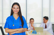 © amornchaijj - Portrait young Asian female doctor smiling with background of a senior male doctor, a young female doctor are meeting in a meeting room in the hospital.