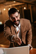 © JustLife - Young businessman giving a handshake in the office. Smiling businessman offering hand for handshake