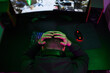 © snedorez - Gamer or streamer in headphones with microphone sits at home in neon light and plays at pc