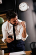 © JustLife - Businessman in office using the phone. Happy man typing a message..