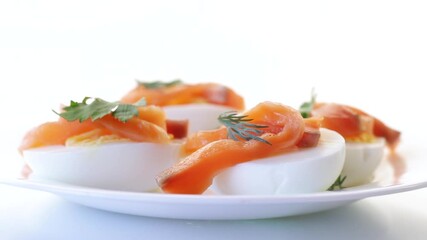 Wall Mural - halves of boiled eggs with pieces of salted salmon on white background