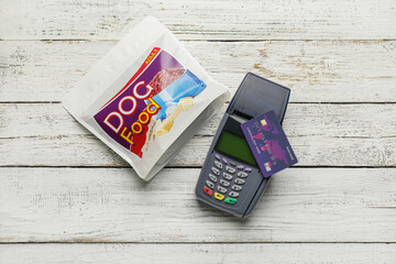 Sticker - Payment terminal with credit card and pet food on light wooden background