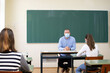 © erika8213 - Teacher and his students wearing protective face mask in the classroom. Social distace and classroom safety during coronavirus epidemic