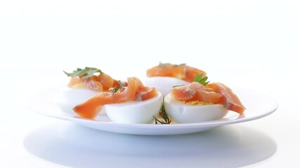 Wall Mural - halves of boiled eggs with pieces of salted salmon on white background