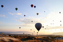 Hot Air Balloons Flying Over Landscape Against Sky During Sunset