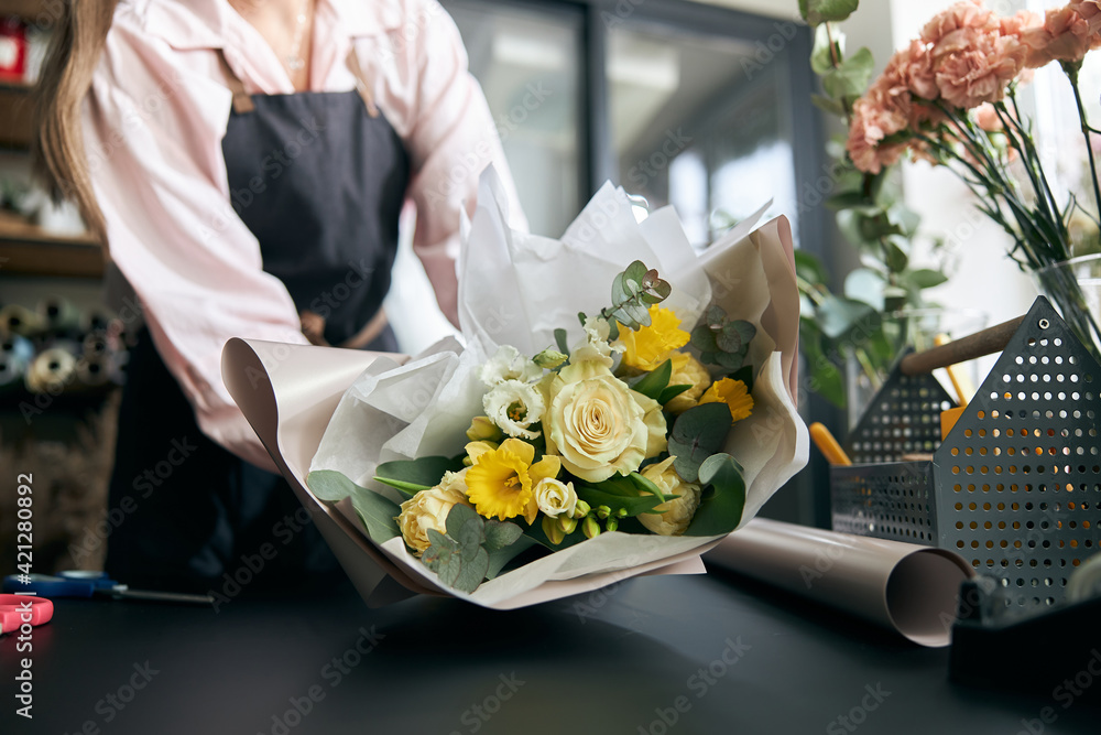 Portrait of successful modern florist wearing apron, creating beautiful bouquet of colorful different flowers in modern interior floral shop. Close up. - obrazy, fototapety, plakaty 