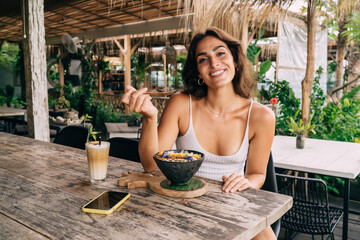 Wall Mural - Cheerful woman enjoying exotic food in resort outdoor cafeteria