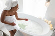 © Wavebreak Media - Smiling african american woman sitting on the edge of bathtub in bathroom
