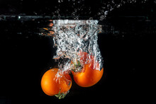 Tomatoes Splashing In Water On A Black Background