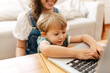 Boy learning using laptop with mom at home