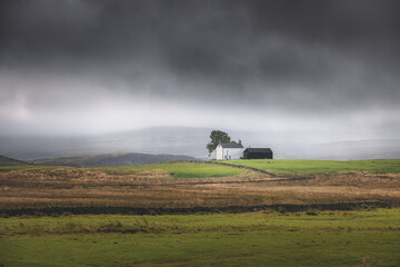 Wall Mural - Lone, secluded farmhouse on a stormy, moody English countryside rural landscape in the North Pennines AONB, England UK.