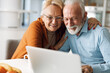 © Goran - Embraced senior couple using laptop at home