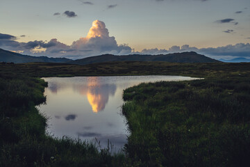 Wall Mural - scenic sunset landscape with yellow big cloud in form of explosion above mountain lake. awesome gian