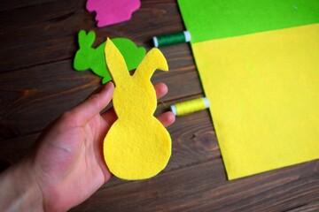 Wall Mural - Girl sews easter bunnies from felt on a wooden background